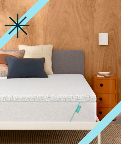 Tuft and Needle mattress in a white bed frame with 3 pillows on top of it. 