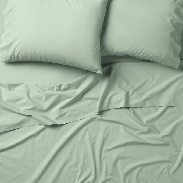 Tuft and Needle green bedding, two pillows encased in 2 green pillow cases on top of 2 sheets.