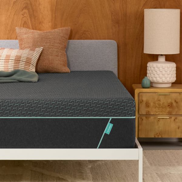 Tuft and Needle Mint Hybrid Mattress in a white bed frame with 2 pillows and green blanket on top it