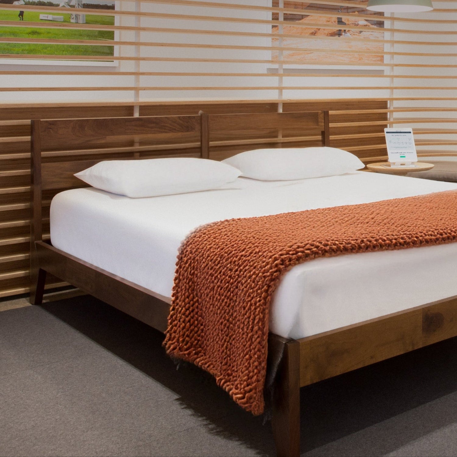 Tuft & Needle store with a wooden bed frame, mattress, blanket, and modern slatted wood room dividers.